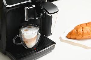 moderno café máquina con vaso taza de latté en blanco mármol encimera en cocina foto