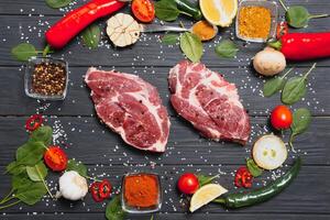 Raw pork meat with spices and vegetables on wooden table. photo