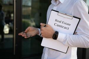 Male Realtor Standing Outside Residential Property Holding Keys photo