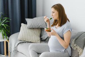 hermosa sano embarazada mujer comiendo vegetal ensalada foto