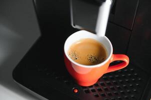 Modern espresso coffee machine with a cup in interior of kitchen closeup photo