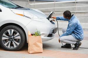 africano americano hombre cargando su eléctrico coche. foto