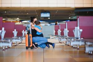 mamá con un pequeño hijo y un maleta a el aeropuerto. viaje concepto foto