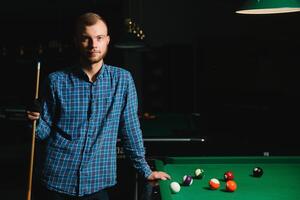 portrait of a young man playing billiards photo