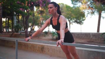 a woman is doing exercise outdoor by leaning on a railing video