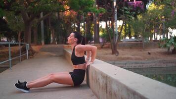 a woman is doing exercise on a concrete bench in a park video