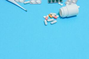 Scattered white pills on blue table.Medical, pharmacy and healthcare concept. Blue background white pills with a medical statoscope, top view photo