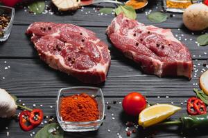 Raw pork meat with spices and vegetables on wooden table. photo