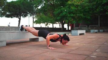 a woman is doing exercise on a concrete bench in a park video