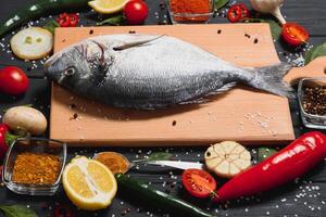 Raw fish cooking and ingredients. Dorado, lemon, herbs and spices. Top view with copy space on table photo