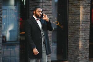 Fashion portrait of a handsome young African American business man walking outdoors in a casual pose. photo