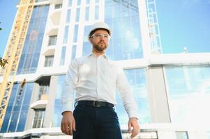 retrato de un joven arquitecto o ingeniero en un construcción sitio foto