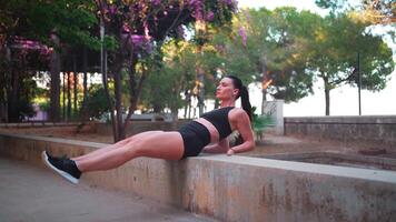 a woman is doing exercise on a concrete bench in a park video