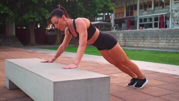 a woman is doing exercise on a concrete bench in a park video