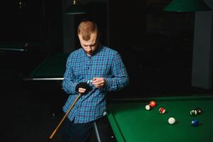 joven jugando billar en el club de billar oscuro foto