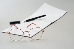 Blank diary, pen, and glasses on white background photo