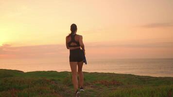 a woman holding Ukrainian flag wearing a black top and shorts is running along the beach video