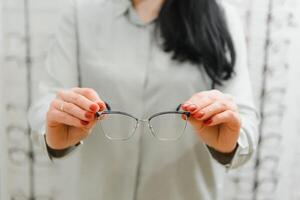 salud cuidado, vista y visión concepto - contento mujer elegir lentes a óptica almacenar. foto