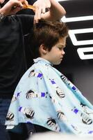 alegre caucásico chico consiguiendo peinado en barbería foto