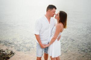 Vacation couple walking on beach together in love holding around each other. Happy interracial young couple, Asian woman and Caucasian man. photo