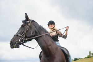 hermosa niña montando un caballo en campo. foto