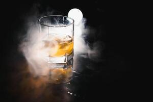 whiskey with ice on black background with smoke photo