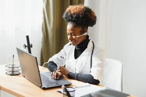 africano hembra médico consultante paciente hacer en línea cámara web vídeo llamada en ordenador portátil. negro mujer terapeuta videoconferencia en remoto computadora cuidado de la salud telemedicina virtual charlar. telesalud videollamada foto