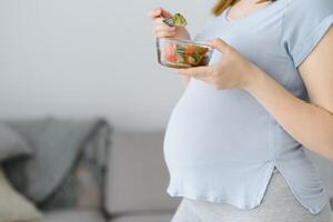 Beautiful healthy pregnant woman eating vegetable salad photo