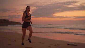 une femme fonctionnement sur le plage à le coucher du soleil video