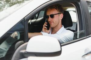 Test driving of new generation electro vehicle with self driving system. Handsome Caucasian man sitting behind the wheel of new modern car and smiling at camera. photo