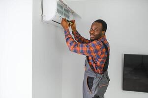 African American electrician repairing air conditioner indoors photo