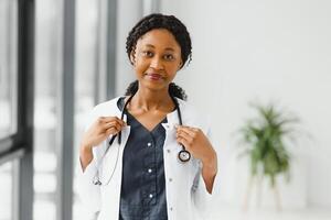 retrato de hembra africano americano médico en pie en su oficina a clínica. foto