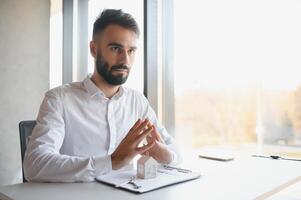 Portrait of a young realtor in the office at the table. Real estate sales concept. photo