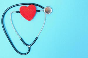 Close-up of a heart and a stethoscope on a blue background, top view. Global health care concept. caring for heart health. treatment with tablets and ampoules. photo