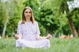 pregnant woman doing yoga in the park. sitting on the grass. photo