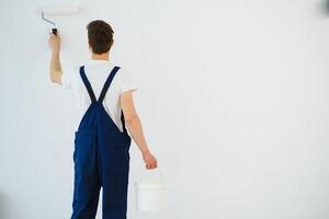 The painter is painting a wall in a room with a roller. photo