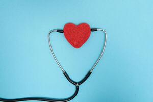 Global healthcare concept.Stylish doctor with heart on blue background.Close-up of red heart and stethoscope on a blue background. Listen to the heart with statoscope photo