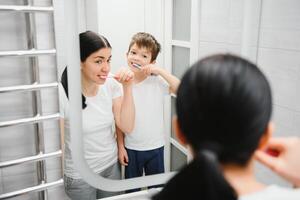 cute mother teaching kid boy teeth brushing photo