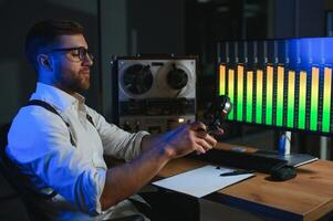 A male spy listens and records conversations on a reel-to-reel tape recorder photo