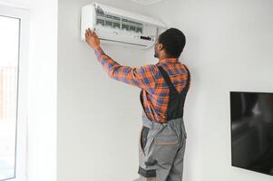 profesional reparador instalando aire acondicionador en un habitación foto