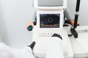 Modern medical equipment. Close up of ophthalmologist using auto refractometer while examining child eyes. photo