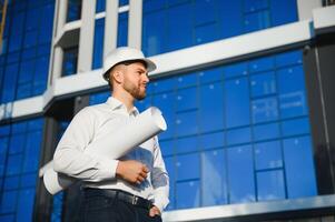 Engineer next to building cranes. Concept - large construction project. Architect directs the construction process. Drawings and tablet in the hands. photo