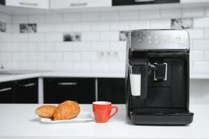 Modern espresso coffee machine with a cup in interior of kitchen closeup photo