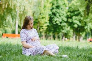 Beautiful pregnant woman relaxing in the park photo