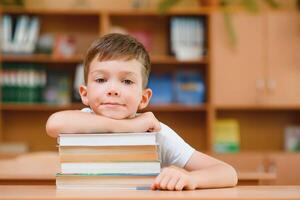 education and school concept - smiling little boy with many books at school photo