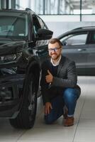 visitando coche concesión. hermoso barbado hombre es acariciando su nuevo coche y sonriente foto