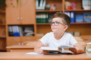 Elementary school boy at classroom desk trying to find new ideas for schoolwork. photo