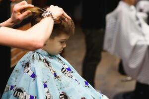 alegre caucásico chico consiguiendo peinado en barbería foto