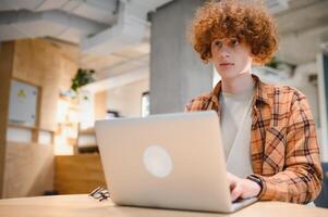 Caucasian hipster guy enjoying distance job in coffee shop, male freelancer in trendy glasses sitting in cafeteria with modern laptop device photo