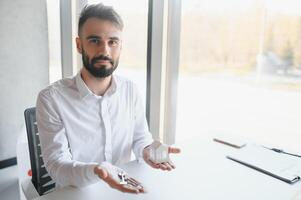 Portrait of a young realtor in the office at the table. Real estate sales concept. photo